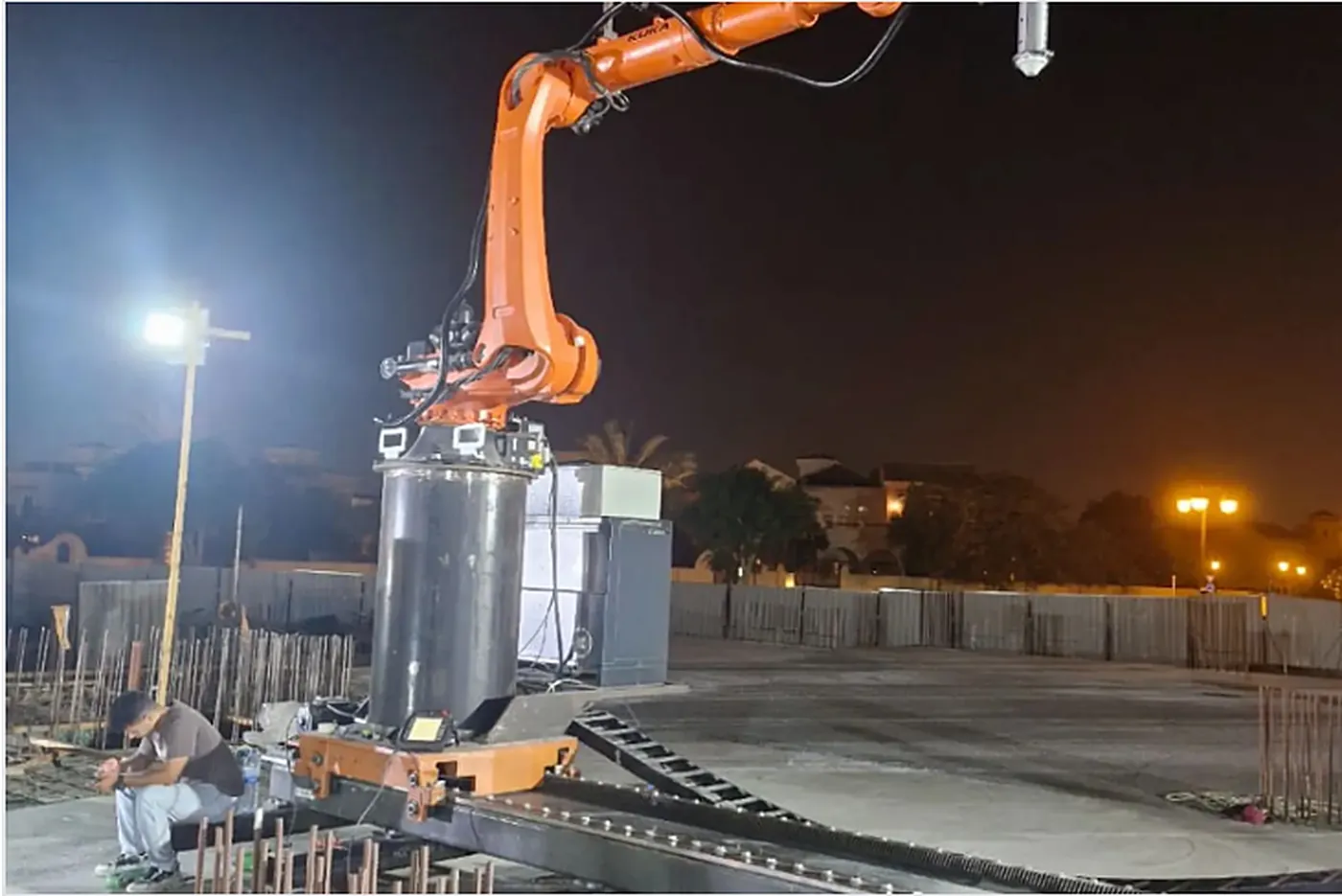 Robotic arm printing concrete on site at night